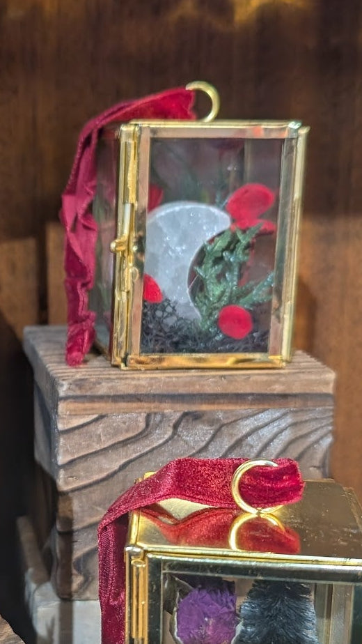 Decorative boxes with gold frames and red ribbons on a wooden surface.